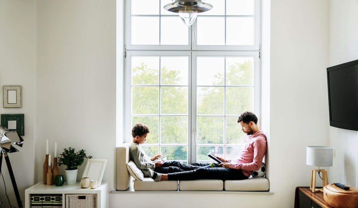 A man and child sit in window seat reading