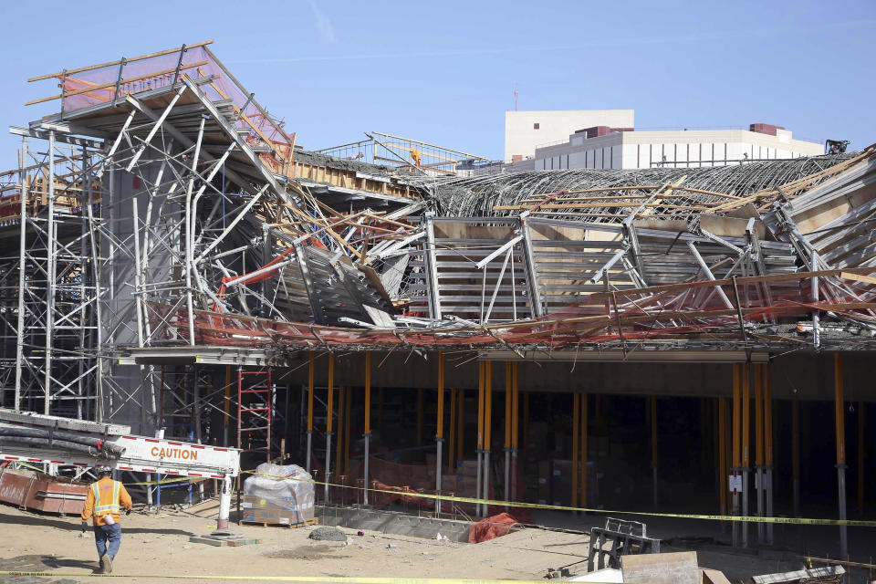 A worker walks near the site where section of a parking structure under construction collapsed Friday March 28, 2014 in Los Angeles. No one was trapped or hurt, authorities said. (AP Photo/Nick Ut)