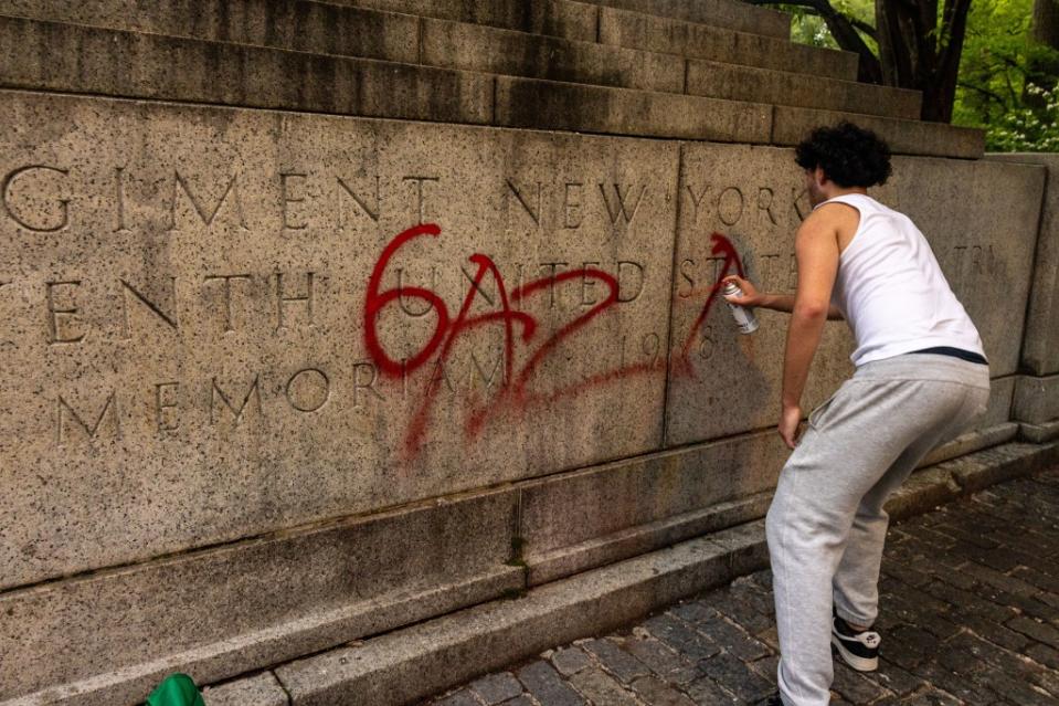 A vandal scrawls graffiti on a World War I memorial in Central Park on Monday. Getty Images