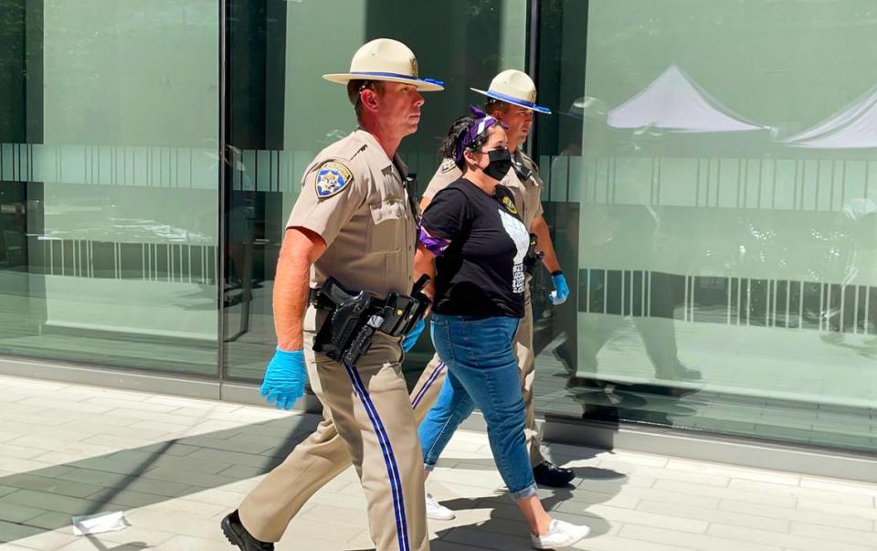 Sacramento City Councilwoman Katie Valenzuela is detained by CHP officers on Wednesday at an SEIU Local 1000 protest at the Capitol swing space offices on O Street in downtown Sacramento.