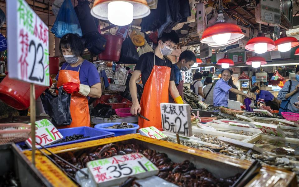 Vendors wearing masks sell seafood on Xihua Farmer's Market in Guangzhou - Shutterstock