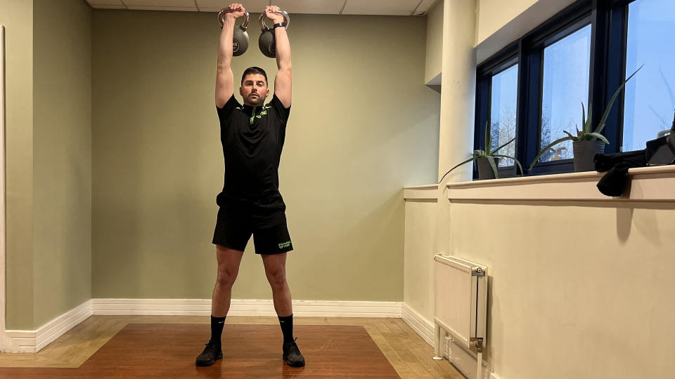 Sam Quinn, a strength coach from Nuffield Health, demonstrates a kettlebell shoulder press