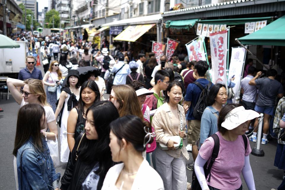 FILE - Visitors stroll at Tsukiji Outer Market on June 7, 2024, in Tokyo. The former Tsukiji Fish Market is one of the popular tourist spots in Tokyo. The site of Tokyo’s famed Tsukiji fish market, left empty after it was razed six years ago, will be replaced by a scenic waterfront stadium and glistening skyscrapers according to plans for its redevelopment that are facing some staunch opposition. (AP Photo/Eugene Hoshiko, File)