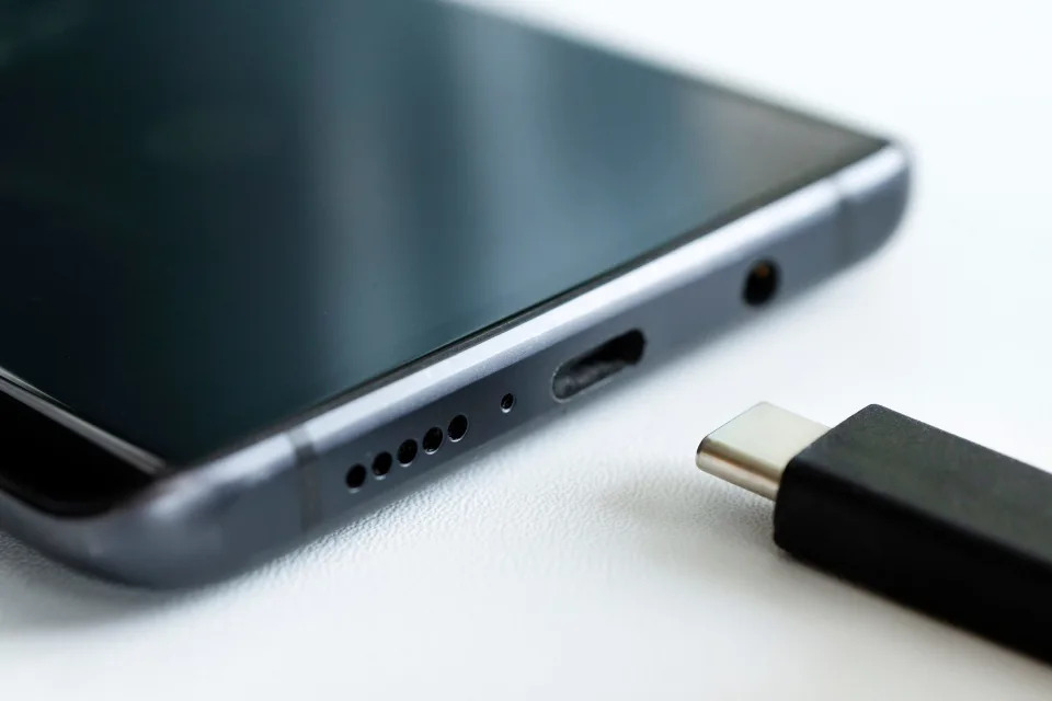 A smartphone with a USB-C cord for charging.
