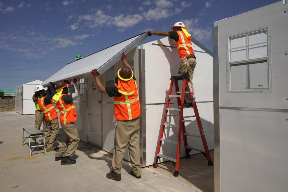 Workers put a roof on one of the Pallet sleeping cabins being built at the Sacramento County's Safe Stay Community in Sacramento, Calif., on Wednesday, July 27, 2022. The safe community was designed to provide 100 cabins for homeless people to sleep in, with running power and sanitation available. Sacramento County had more than 9,200 people experiencing homelessness during this year's annual count conducted in February 2022.(AP Photo/Rich Pedroncelli)