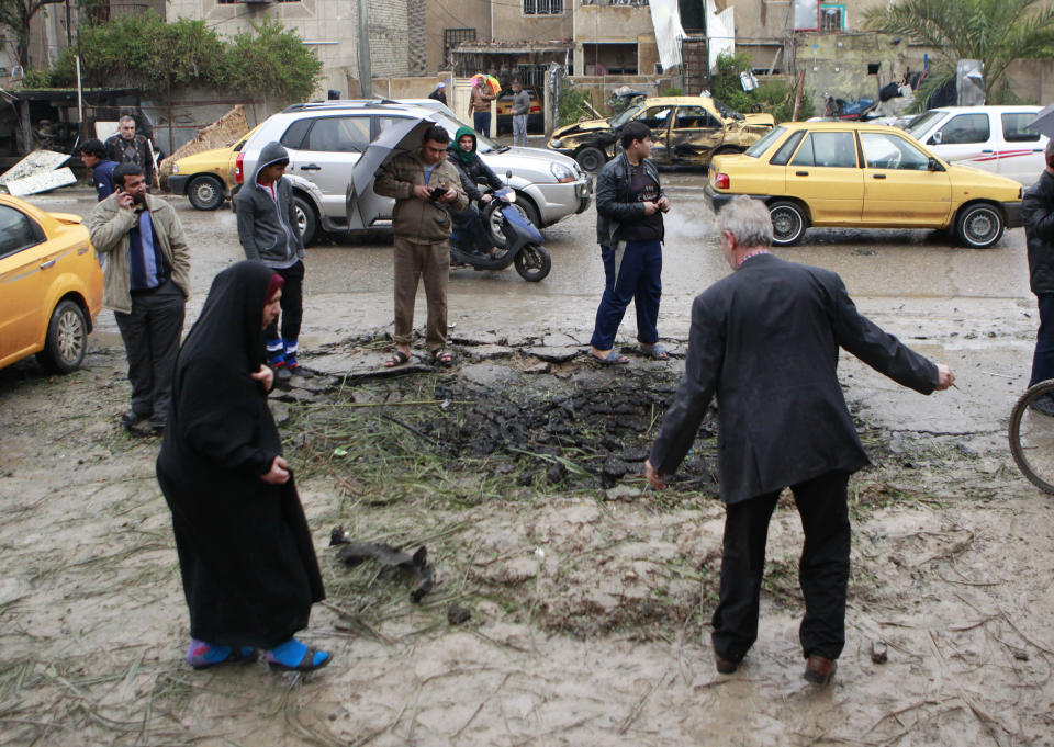 Iraqi civilians inspect a crater caused by a car bomb in a commercial area in the northern Hurriyah neighborhood of Baghdad, Iraq, Monday, Feb. 3, 2014. Iraqi officials say car bombings on Monday in and near Baghdad have killed and wounded scores of people. (AP Photo/Hadi Mizban)