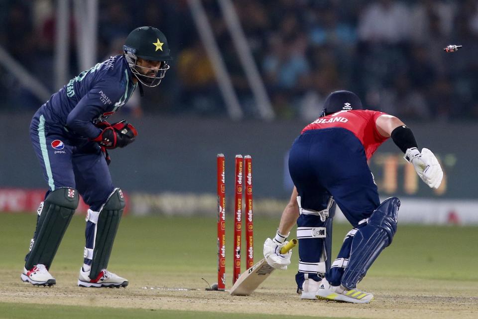 Pakistan's Mohammad Rizwan, left, removes bails to run out to England's Ben Duckett during the seventh twenty20 cricket match between Pakistan and England, in Lahore, Pakistan, Sunday, Oct. 2, 2022. (AP Photo/K.M. Chaudary)