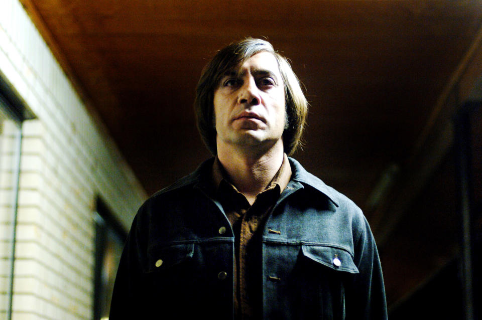 Anton Chigurh wearing a jean jacket with a serious look on his face