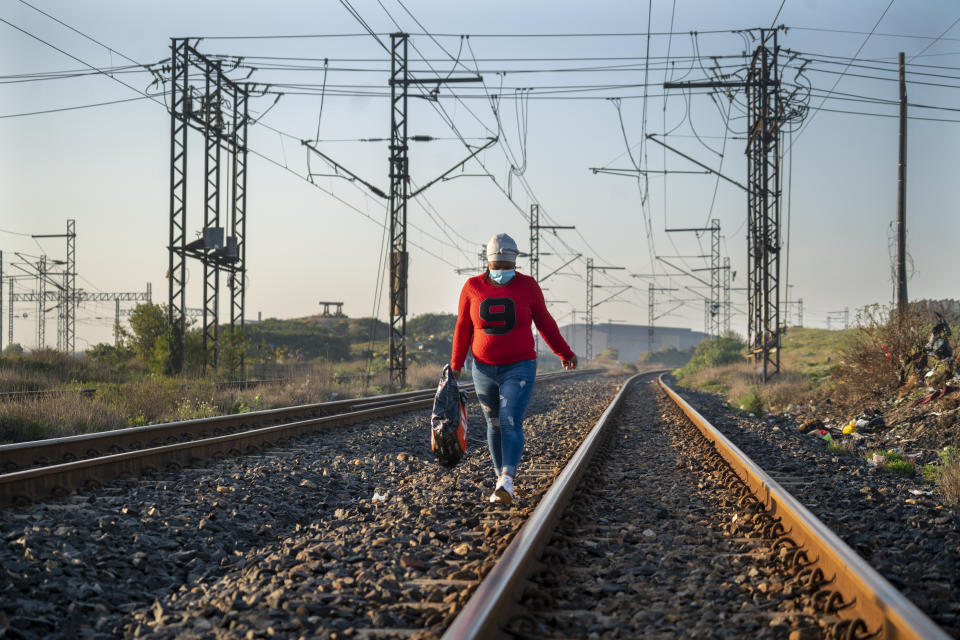 A woman walks towards a COVID-19 vaccination train parked at the Swartkops railroad yard outside Gqeberha, South Africa, Thursday Sept. 23, 2021. South Africa has sent a train carrying COVID-19 vaccines into one of its poorest provinces to get doses to areas where healthcare facilities are stretched. The vaccine train, named Transvaco, will go on a three-month tour through the Eastern Cape province and stop at seven stations for two weeks at a time to vaccinate people. (AP Photo/Jerome Delay)