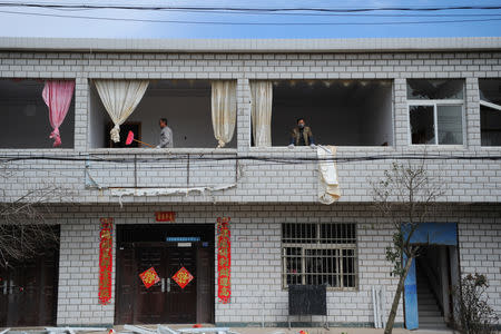 A man wearing a mask looks on next to a man carrying a broom at a damaged building, following an explosion at a pesticide plant owned by Tianjiayi Chemical nearby, in Xiangshui county, Yancheng, Jiangsu province, China March 22, 2019. REUTERS/Stringer