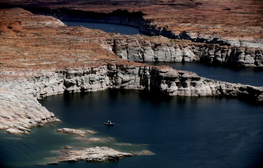 LAKE POWELL, UTAH - MAY 16, 2022. A boat sits in a cove on Lake Powell in Utah, where white surfaces along the banks show previous water levels in the second largest reservoir in the U.S. The lake is popular with boaters and annually attracts more than 2 million visitors. It has been vastly reduced by relentless drought for more than a decade. In 2022 Lake Powell was at 3,522.24 feet above sea level with a capacity of about 22 percent. This is its lowest level since it was filled 59 years ago. (Luis Sinco / Los Angeles Times)