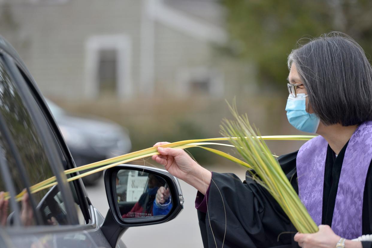 HARWICH CENTER -- 03/28/21 -- The Rev. Dianne Arakawa, interim pastor, hands palms to a passenger. This is the second year church officials have hosted the event due to the ongoing pandemic.