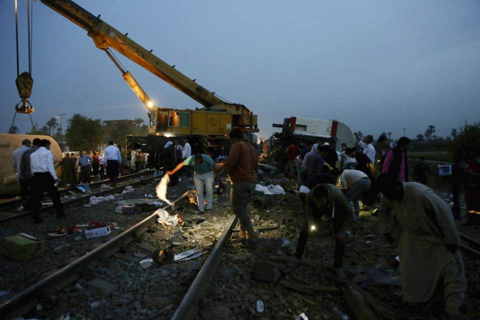 People search for belongings in the aftermath of a passenger train that derailed injuring around 100 people, near Banha, Qalyubia province, Egypt, Sunday, April 18, 2021. The train was travelling to the Nile Delta city of Mansoura from the Egyptian capital, the statement said. (AP Photo/Fadel Dawood)