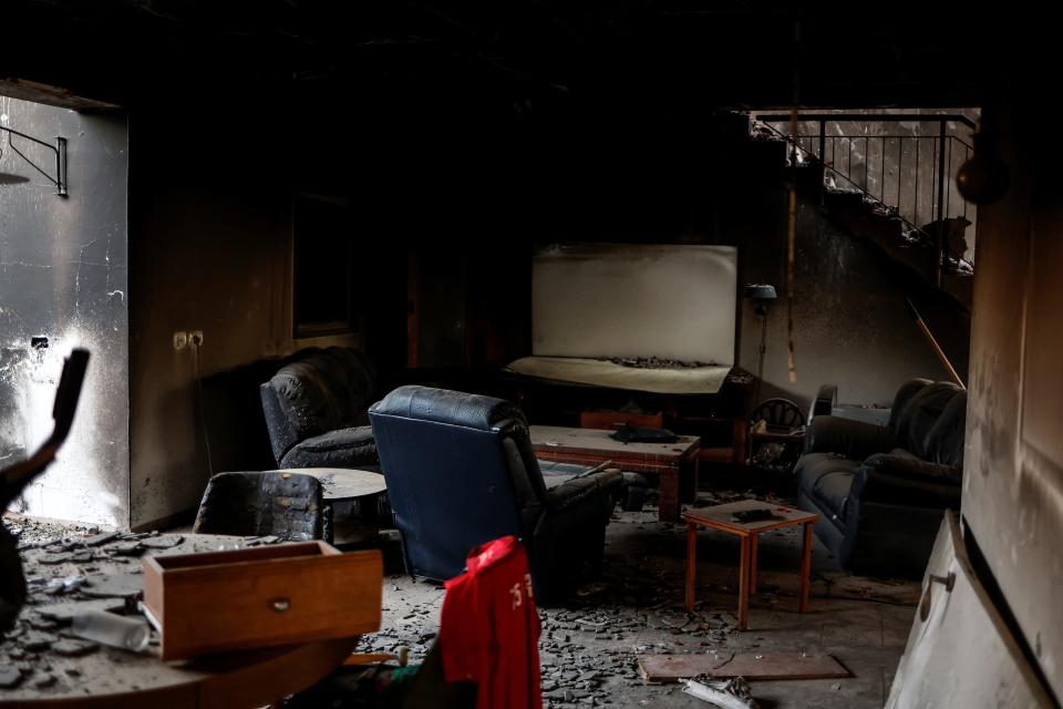 A photo of a burned living room in a house with debris on the floor and destroyed furniture.