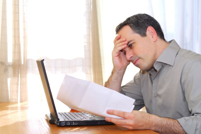 B2X945 Man sitting at his desk with a laptop and bills looking concerned. Image shot 2006. Exact date unknown.  man; businessman