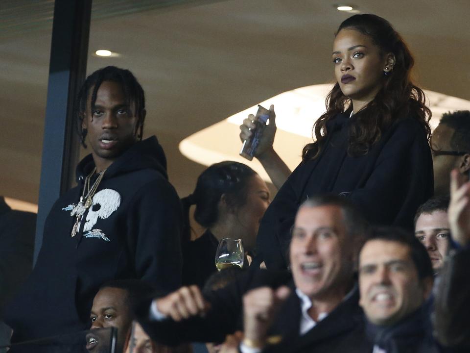 Rihanna and Travis Scott (left) attend the French Ligue 1 match between Paris Saint-Germain FC (PSG) and Olympique de Marseille at Parc des Princes stadium on October 4, 2015 in Paris, France