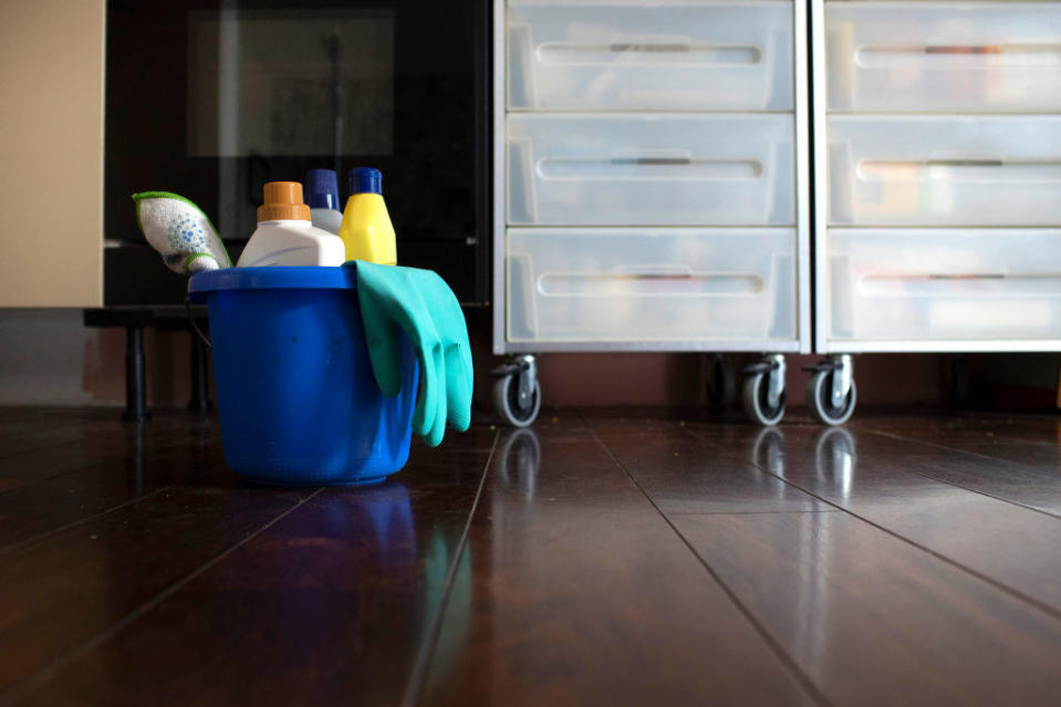 Household cleaning items in a bucket alongside plastic file cabinets