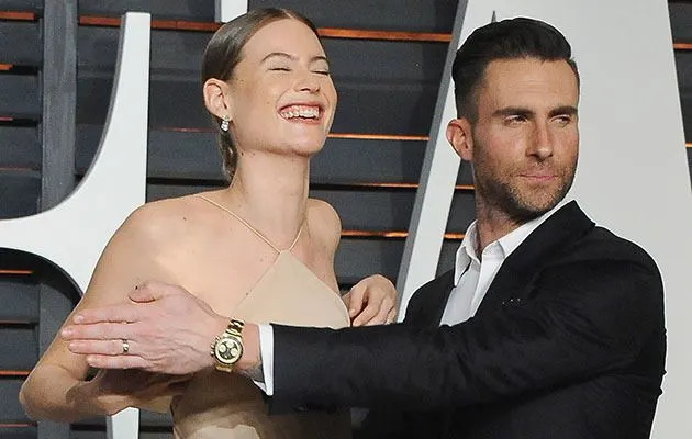 Adam Levine protects his wife's modesty on the red carpet. Getty Images.