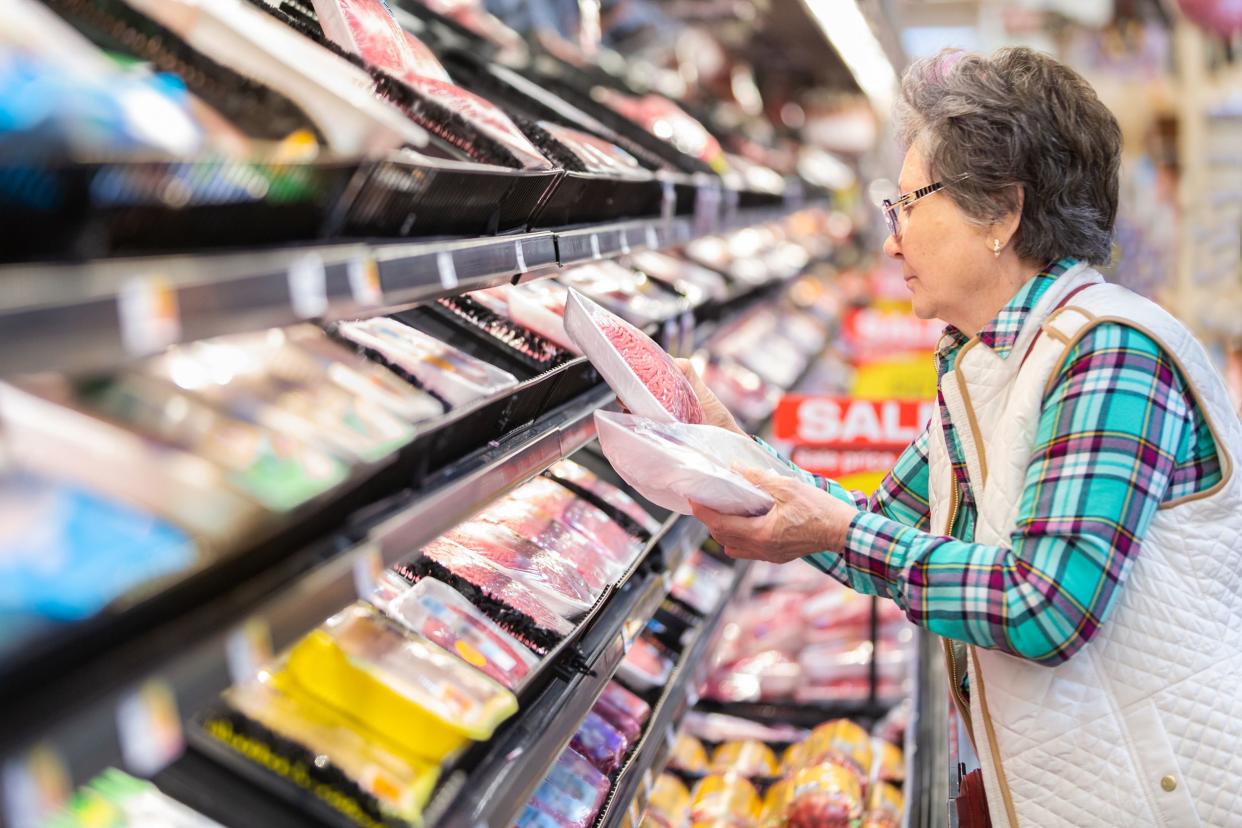 senior woman buying ground beef at grocery store