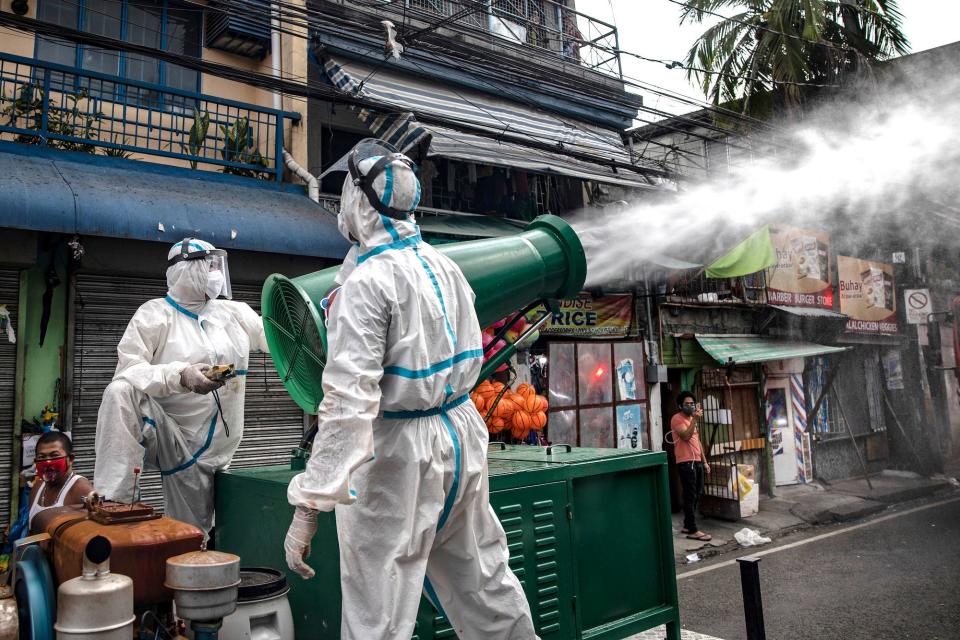 Disinfection workers spray disinfectant from a water cannon along a street at a suburban area on March 23, 2020 in San Juan, Metro Manila, Philippines.