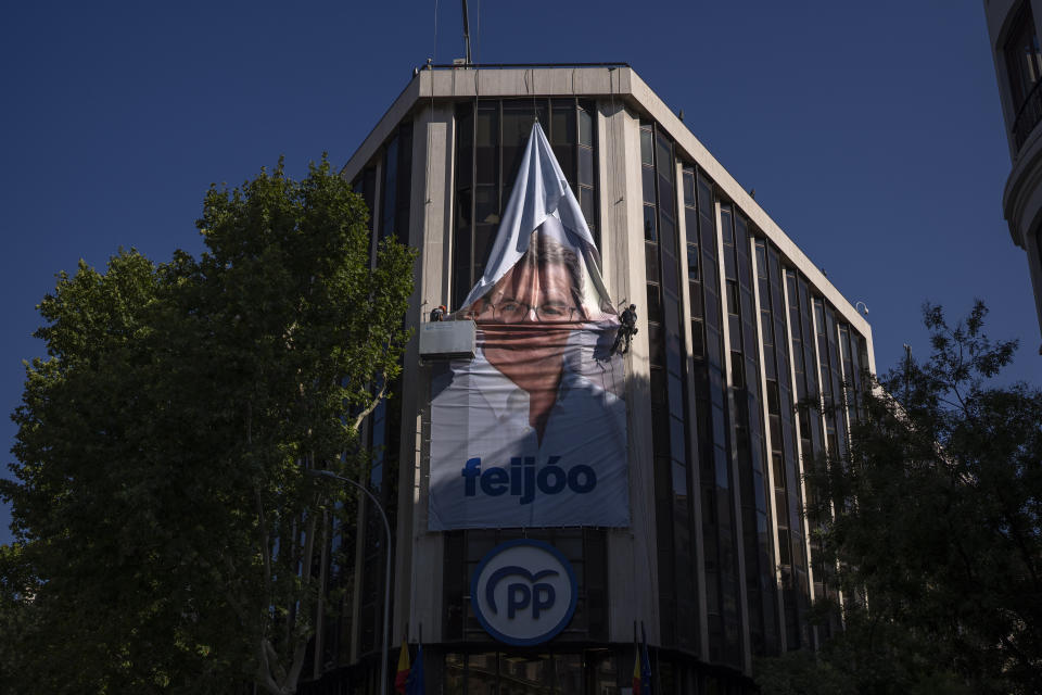 Workers remove an electoral poster showing Alberto Feijoo, leader of the mainstream conservative Popular Party, at the party headquarters in Madrid, Spain, Monday, July 24, 2023. Spaniards woke up Monday to find their country in political disarray after elections a day earlier left no party with a clear path to forming a government. (AP Photo/Emilio Morenatti)