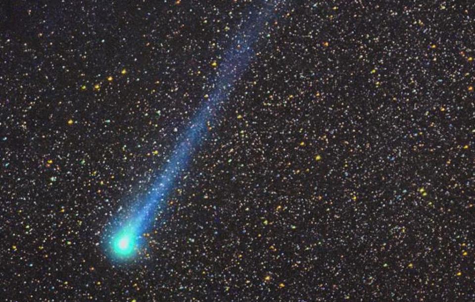 A blue comet against a black night sky with many stars visible.