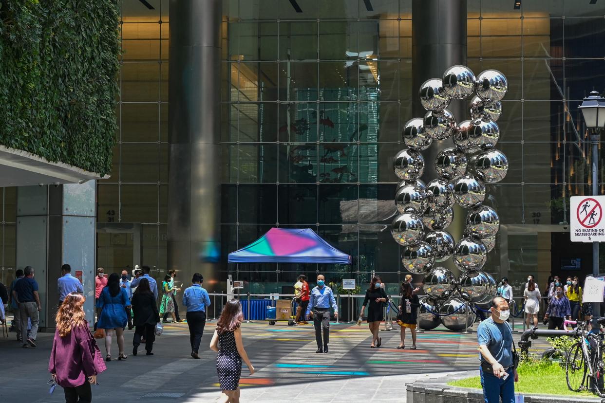 People walk along a promenade at the Raffles Place financial business district in Singapore.