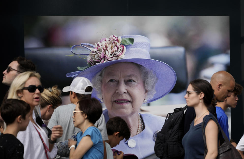 Passers by walk in front of a picture of Queen Elizabeth II, in London, Sunday, Sept. 11, 2022. Queen Elizabeth II, Britain's longest-reigning monarch and a rock of stability across much of a turbulent century, died Thursday Sept. 8, 2022, after 70 years on the throne. She was 96. (AP Photo/Christophe Ena)