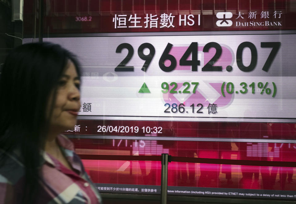 A woman walks past a bank electronic board showing the Hong Kong share index at Hong Kong Stock Exchange Friday, April 26, 2019. Shares were mostly lower in Asia on Friday after an overnight decline on Wall Street spurred by disappointingly weak earnings reports from 3M and other industrial companies. (AP Photo/Vincent Yu)