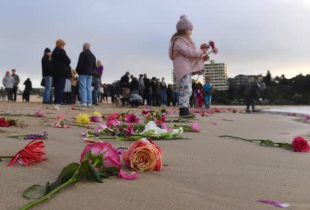 Relatives and friends of Justine Damond, who was shot by a Minneapolis police officer over the weekend, stand near flowers after they held a vigil at Sydney's Freshwater Beach in Australia, July 19, 2017. AAP/Dean Lewins/via REUTERS