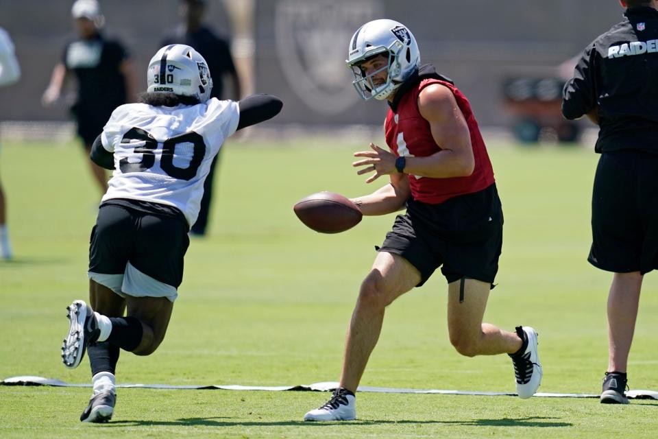 Las Vegas Raiders quarterback Derek Carr (4) looks to hand off to running back Jalen Richard (30) during NFL football practice Wednesday, June 2, 2021, in Henderson, Nev.