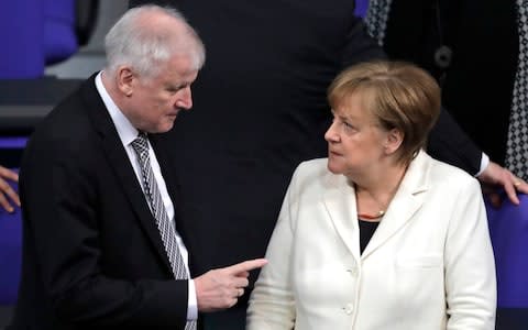 German Interior Minister Horst Seehofer, left, talks to German Chancellor Angela Merkel in the German parliament in Berlin - Credit: AP Photo/Markus Schreiber