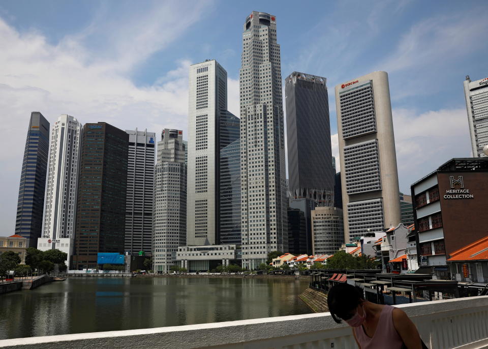 A woman wearing a protective face mask passes the city skyline during the coronavirus outbreak (COVID-19) outbreak in Singapore June 10, 2021.   REUTERS/Edgar Su