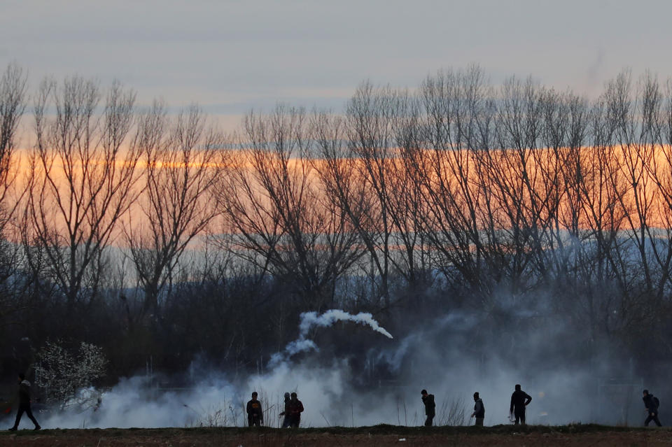 Migrants are seen in a smoke of tear gas at the Turkish-Greek border in Pazarkule on Friday, March 6, 2020. Clashes erupted anew on the Greek-Turkish border Friday as migrants attempted to push through into Greece, while the European Union's foreign ministers held an emergency meeting to discuss the situation on the border and in Syria, where Turkish troops are fighting. (AP Photo/Darko Bandic)