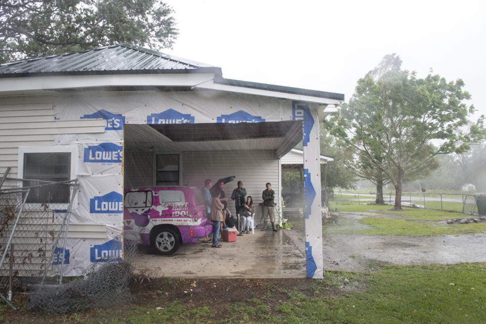 The Lafleur family of Bell City, La., gathers in their garage near where a wall was destroyed by Hurricane Laura several weeks ago, as they watch the arrival of Hurricane Delta, Friday, Oct. 9, 2020. (Chris Granger/The Advocate via AP)