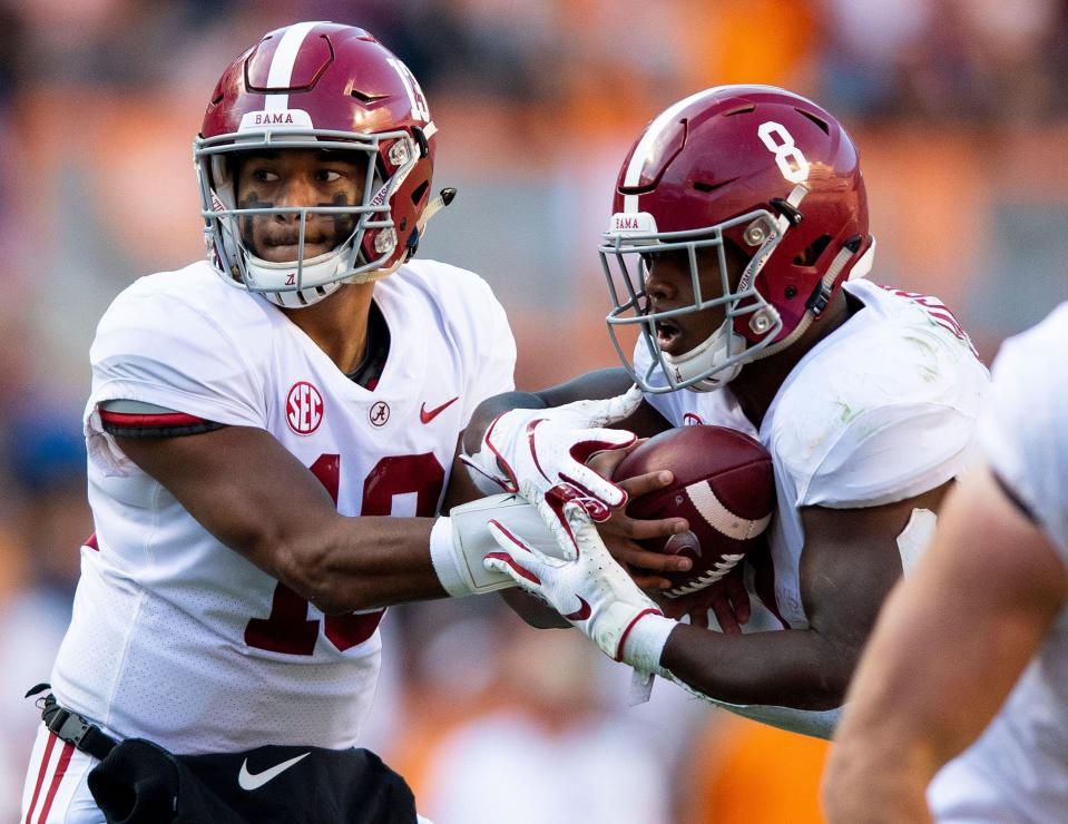 Alabama quarterback Tua Tagovailoa hands off the ball to running back Josh Jacobs.