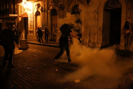 A demonstrator throws back a tear gas canister during clashes with the police in a protest calling for the resignation of Governor Ricardo Rossello in San Juan