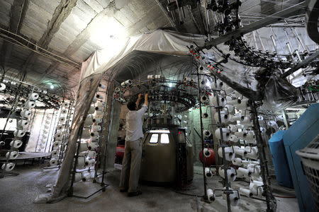 A worker works on a cotton spinning machine in government-controlled al-Hamadaniah district of Aleppo, Syria July 12, 2017. Picture taken July 12, 2017. REUTERS/Omar Sanadiki