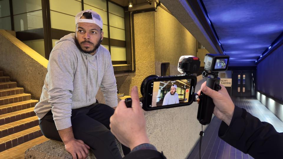 Man sitting on a wall being filmed by a phone