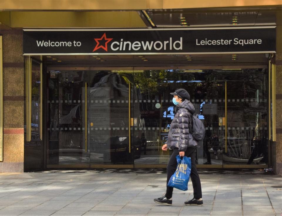 London, United Kingdom - October 5 2020: A woman with a protective face mask walks past Empire Cinema, operated by Cineworld, on Leicester Square