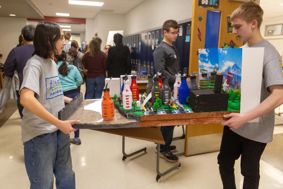 Katie Bond and Nick Horton, eighth-graders at Seaman Middle School, carry their city model out of a classroom after presenting at the Future City regional competition Saturday at the school.