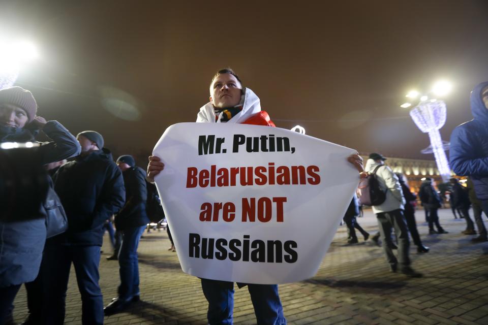 A Belarusian demonstrator holds a poster as other gather to protest closer integration with Russia which protesters fear could erode the post-Soviet independence of Belarus, in downtown in Minsk, Belarus, Friday, Dec. 20, 2019. The presidents of Belarus and Russia have met to discuss deeper economic ties between the two close allies amid mounting concerns in Minsk that Moscow ultimately wants to subdue its neighbor.(AP Photo/Sergei Grits)