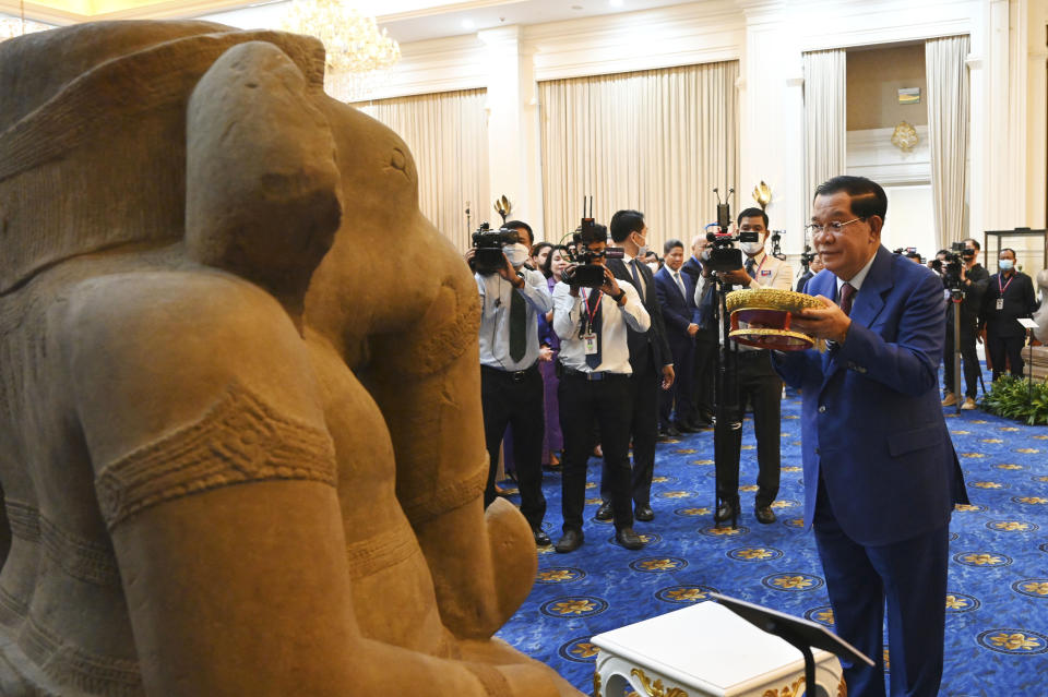 In this photo provided by Kok Ky/Cambodia's Government Cabinet, Cambodian Prime Minister Hun Sen, right, prays in front of a sandstone statue of Ganesha, at Peace Palace, in Phnom Penh, Cambodia, Friday, March 17, 2023. Centuries-old cultural artifacts that had been illegally smuggled out from Cambodia were welcomed home Friday at a celebration led by Prime Minister Hun Sen, who offered thanks for their return and appealed for further efforts to retrieve such stolen treasures. (Kok Ky/Cambodia's Government Cabinet via AP)