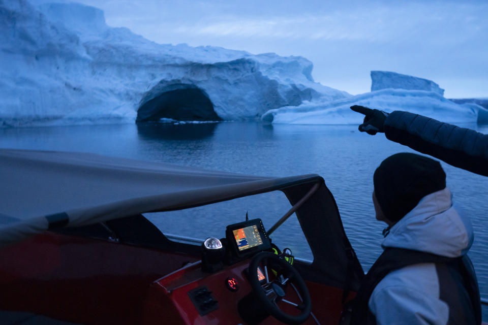 In this Aug. 16, 2019, photo, a boat navigates at night next to a large iceberg in eastern Greenland. Summer 2019 is hitting Greenland hard with record-shattering heat and extreme melt. Scientists estimate that by the end of the summer, about 440 billion tons (400 billion metric tons) of ice, maybe more, will have melted or calved off Greenland's giant ice sheet. (AP Photo/Felipe Dana)