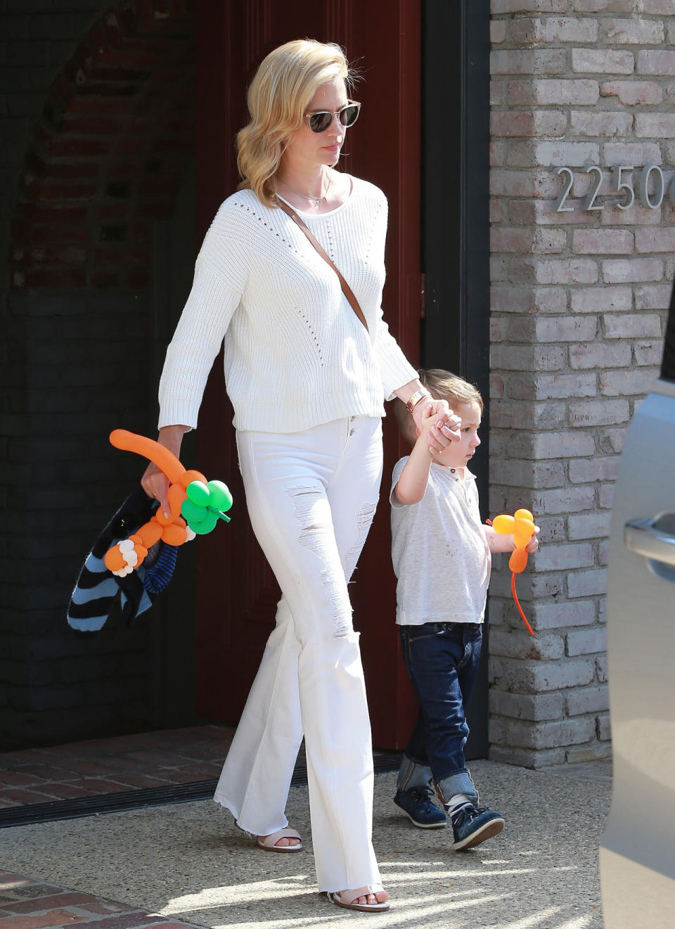 January Jones in a chunky knit sweater and a pair of white ripped jeans.