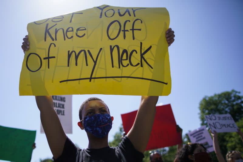 A protester holding a banner takes part in a rally against the death in Minneapolis police custody of George Floyd, in the Brooklyn borough of New York City