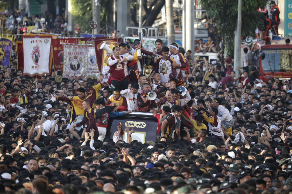 Devotees try to climb the carriage of the Black Nazarene during a raucous procession to celebrate its feast day Thursday, Jan. 9, 2020, in Manila, Philippines. A mammoth crowd of mostly barefoot Filipino Catholics prayed for peace in the increasingly volatile Middle East at the start Thursday of an annual procession of a centuries-old black statue of Jesus Christ in one of Asia's biggest religious events. (AP Photo/Aaron Favila)