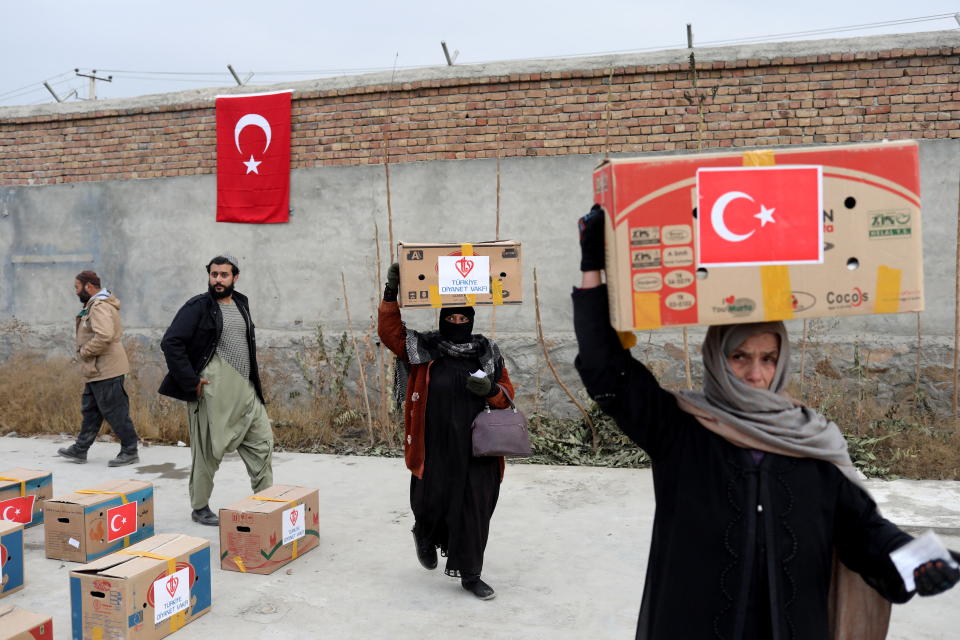 Afghan women carrying packages distributed by a Turkish humanitarian aid group, leave a distribution centre in Kabul, Afghanistan, December 15, 2021. REUTERS/Ali Khara