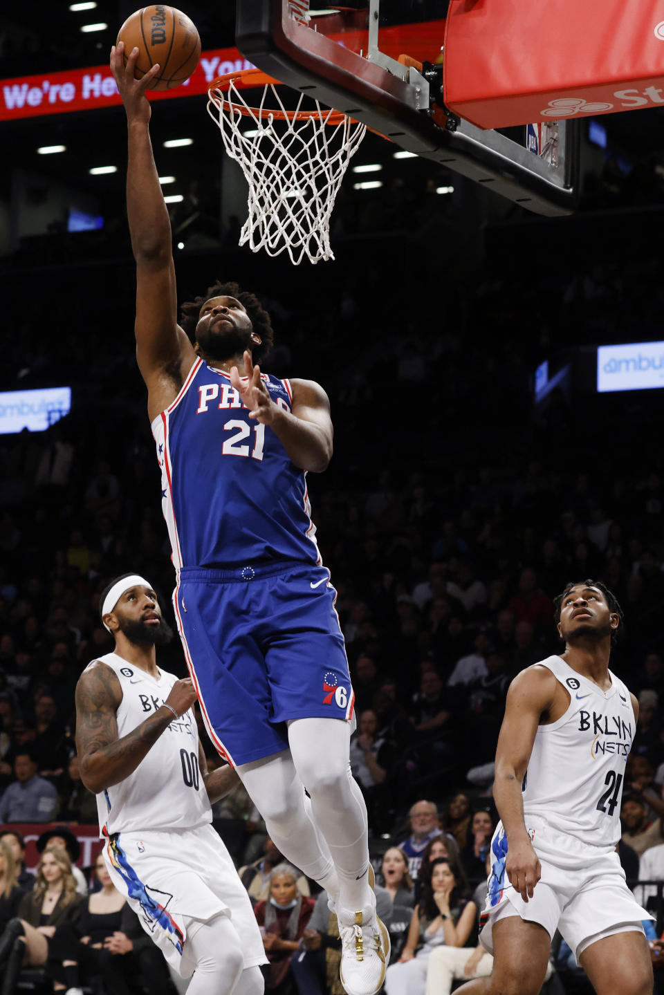 Philadelphia 76ers' Joel Embiid (21) goes to the basket against Brooklyn Nets' Royce O'Neale (00) and Cam Thomas (24) during an NBA basketball game Saturday, Feb. 11, 2023, in New York. (AP Photo/Jason DeCrow)