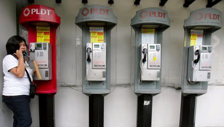 A woman uses a pay phone outside a Philippine Long Distance Telephone Company (PLDT) office in Manila November 3, 2009. REUTERS/Cheryl Ravelo/File Photo